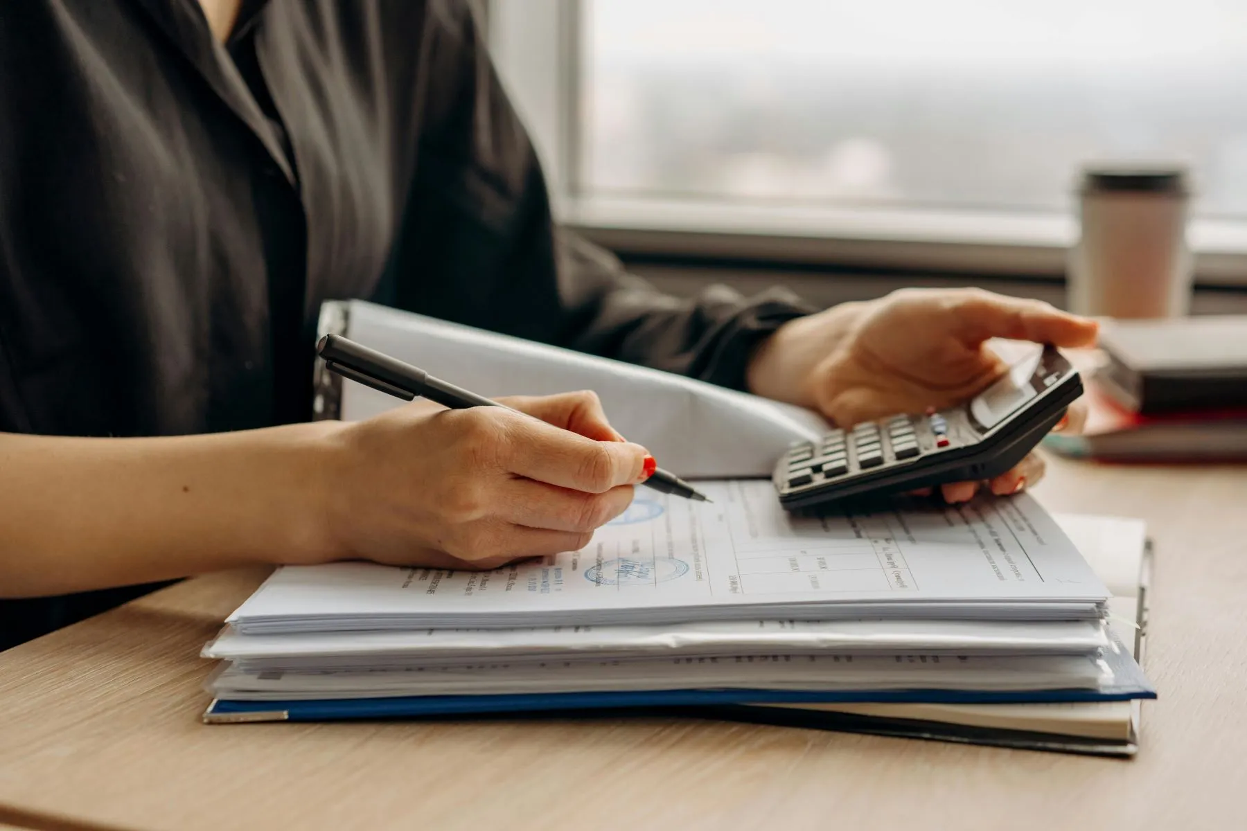 Une femme étudie des documents et tient une calculatrice.